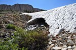 The stream has carved a 20 ft. high snow cavern through a drift, illustrating the hazards of traversing melting snow fields.