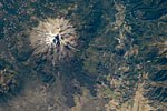 Mt. Shasta from space, 2012 (NASA). North is at the bottom, the town of Mt. Shasta at right. At the bottom, you can really see how the flowing lava shaped the land.